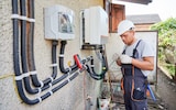 Electrician installing solar panel system on the outside of a house